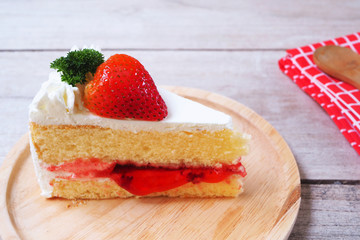 Close up of strawberry milk cake on a wooden plate.