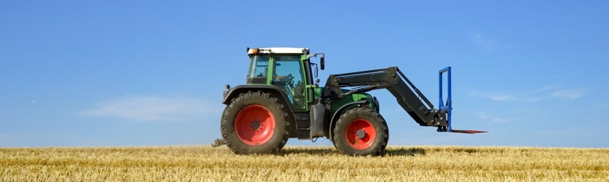Gr&uuml;ner Schlepper mit Frontlader auf einem Stoppelfeld, Banner