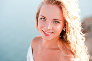 Naklejka premium Smiling blonde girl posing over sea background outdoors. Looking at camera. 20s.