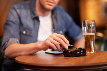 man drinking beer and smoking cigarette at bar