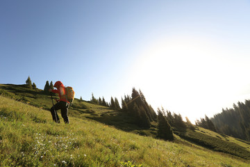 Obraz premium young woman backpacker hiking on beautiful mountain peak