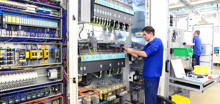 Facharbeiter montiert elektronische Schaltanlage in einer Fabrik // workers mounted switchgear in an industrial plant