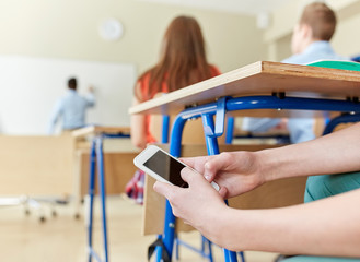 student boy with smartphone texting at school