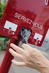 homme prenant sachet pour crottes de chien dans distributeur public (France)