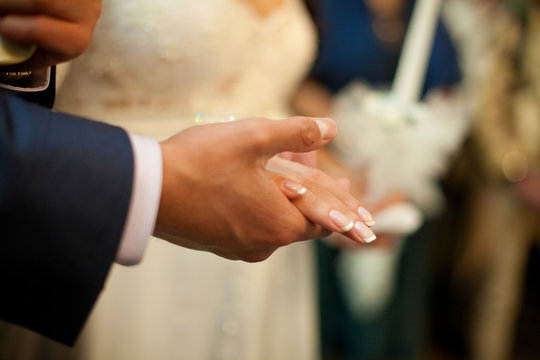 Groom's hand holds bride's palm delicately
