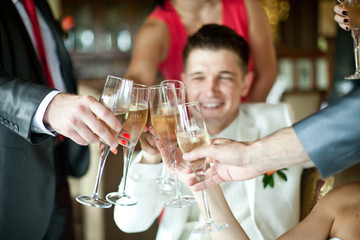 Groom in white suit clangs the glasses with guests