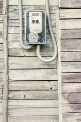 Fototapeta na wymiar Modern electrical meter hanging on the old wooden house in the village outdoors