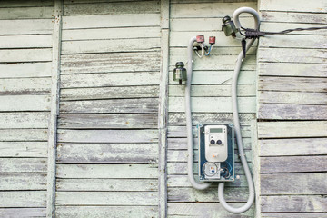 Modern electrical meter hanging on the old wooden house in the village outdoors