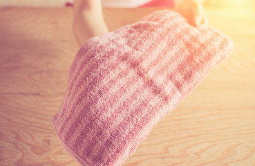 Close-up woman hands putting stack of fresh bath towels on the table. Room service maid cleaning hotel or bedroom.Lens flair in sunlight and warm tone.