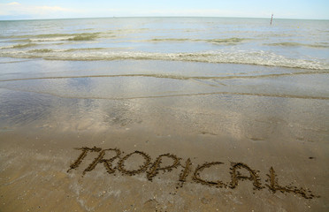 tropical written on the beach sand