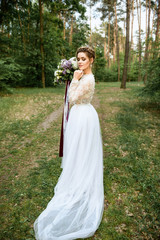 Fototapeta na wymiar bride with a bouquet of color in the woods. wedding dress with long train.