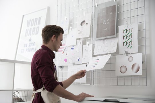 Man Working In Screen Printers Looking At Visual References