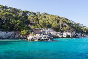Bay with crystal blue water surrounded by cliffs and pine trees