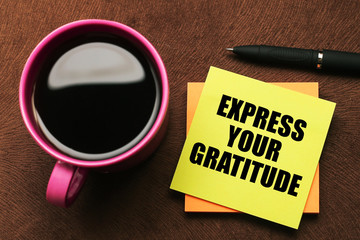 Express your gratitude - motivational slogan on a color sticky note with a cup of coffee