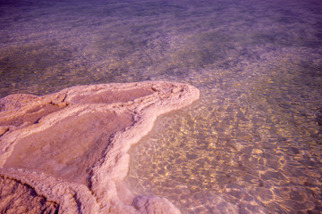 Fototapeta na wymiar Texture of Dead Sea at sunrise. Salty sea shore background in trendy rose violet color