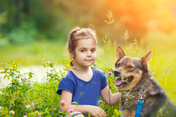 Portrait of happy little girl with dog outdoor. Girl looking at camera