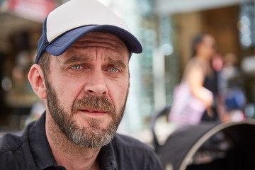Hipster with beard and baseball cap sitting in a street cafe