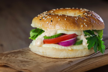 Homemade cheeseburger on wooden plank with fresh vegetables. Clo