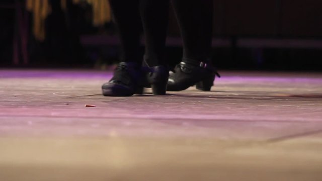 Close up of female dancing feet on stage. Women doing Irish dance with traditional step shoes. Music, tradition and culture of Ireland. Celtic show on wooden floor
