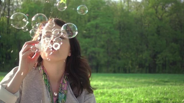 Cute Caucasian Girl Blowing Soap Bubbles In Park