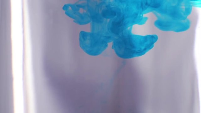 Blue ink dropped into water in slow motion