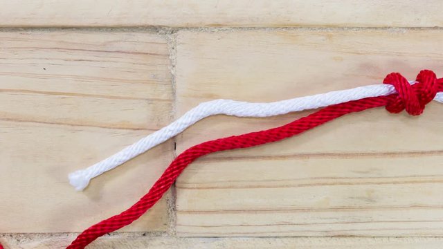 4k stop motion fisherman's knot made with red rope on wooden background.