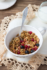 Homemade delicious healthy granola with nuts, seeds, honey and fresh berries in a ceramic cup