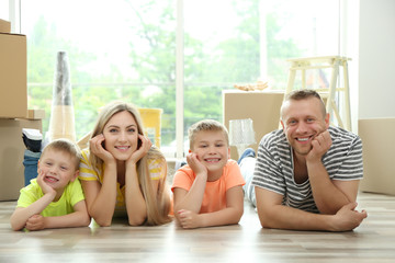 Happy family with cardboard boxes lying on wooden floor