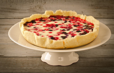 Mix berry tart, pie, cake with raspberries, bilberries, bluberries, red currant and cream on white background