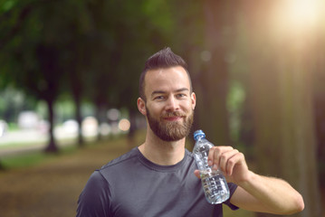 Junger Mann trinkt aus der Flasche Wasser
