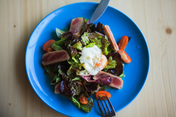 Salad Nicoise on a blue plate ready to be eaten