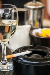 Glass of White Wine With an Ashtray and Cigarette on a Table 