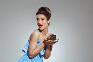 Fotobehang Picture of beautiful pin-up girl holding cake in hands at studio © Cookie Studio