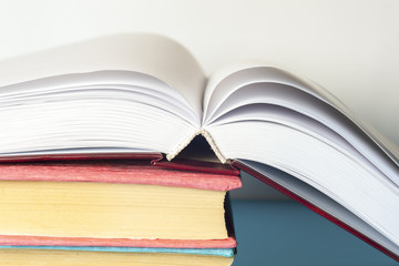 Open book, stack of colorful hardback books on light table. Back