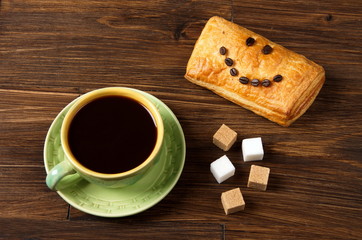 Green cup of coffee with white and brown sugar cubes and puff with a smile of coffee grains