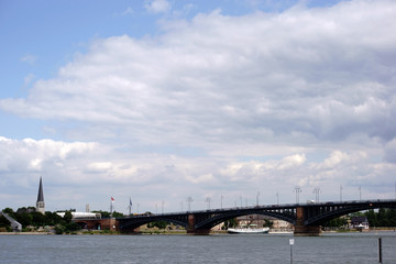 Fototapeta premium Theodor-Heuss-Brücke Mainz / Die Theodor-Heuss-Brücke in Mainz über den Fluss Rhein und den Ufern in Mainz Kastel mit der St. Georg Kirche im Hintergrund.