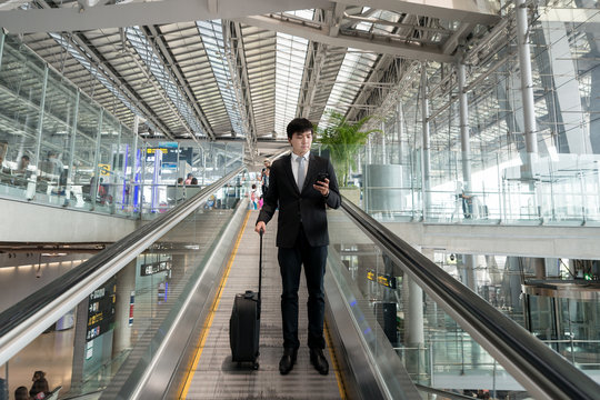 Young Asian business man with luggage in airport.
