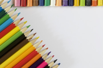 Colored pencils. Located next to the frame on the diagonal. Pastel located along the top of the frame. On a white background.