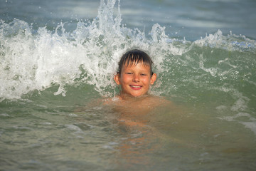 boy frolics in the sea with splashes and waves