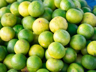 Closeup of fresh organic green lemons for retail sale in local market, Thailand (selective focus)