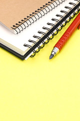 yellow office desk background with pencil and notebooks