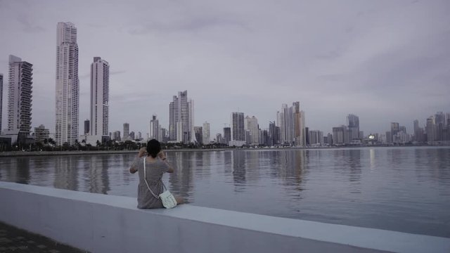Hispanic woman taking pictures of the cityscape on a foggy day, Panama city. 4k