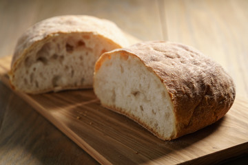 halves of fresh ciabatta on olive cutting board