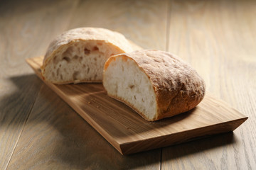 halves of fresh ciabatta on olive cutting board