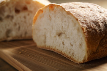 halves of fresh ciabatta on olive cutting board