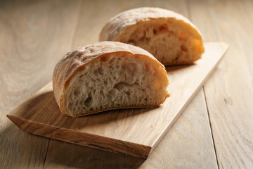 halves of fresh ciabatta on olive cutting board