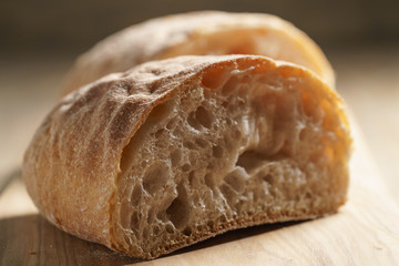 halves of fresh ciabatta on olive cutting board