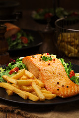 Baked salmon served with french fries.