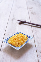 Close up of dried peeled split mung bean on a  square ceramic plate  on a wooden background.