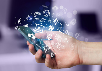 Hand holding smartphone with media icons and symbol